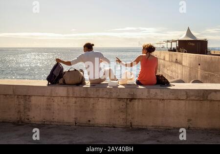 Ein Paar sitzt an einer Meereswand in Funchal, Madeira. Stockfoto