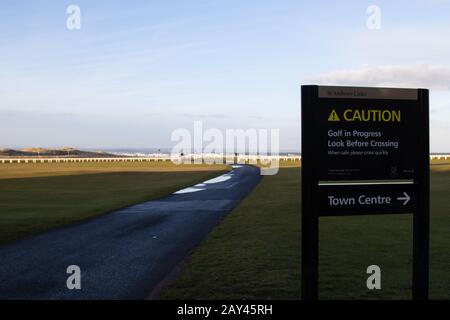 ST ANDREWS, SCHOTTLAND - 13.2.2020 - EIN Blick auf die Straße über den alten Kurs mit einem Warnschild, das im Vordergrund das laufende Golf zeigt Stockfoto
