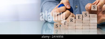 Nahaufnahme der Hand letzte Alphabet der Person des Wortes Stress auf hölzernen Block Stockfoto