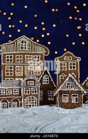 Hausgemachte Lebkuchenstadt mit Bokehhimmel aus blauem samt und weihnachtslichtern als Adventsdekoration für die Familie Stockfoto