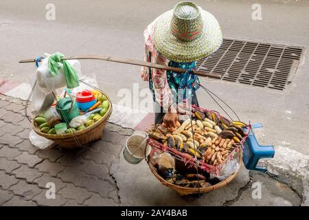 Lebensmittelhändler mit Schulterpole für den Transport in einem zentralen Bezirk von Bangkok, Thailand Stockfoto