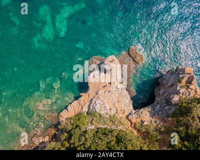 Luftaufnahme der Mogren-Vorgebirge zwischen den Mogren-Stränden. Budva. Montenegro. Zerklüftete Küsten mit schieren Klippen und Blick auf das transparente Meer. Wild Stockfoto