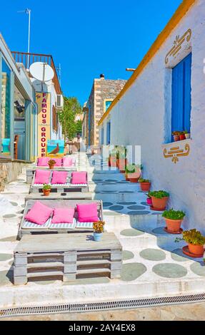 Perdika, Insel Ägina, Griechenland - 14. September 2019: Open-Air-Restaurant at with Couches in the Street in Perdika Stockfoto