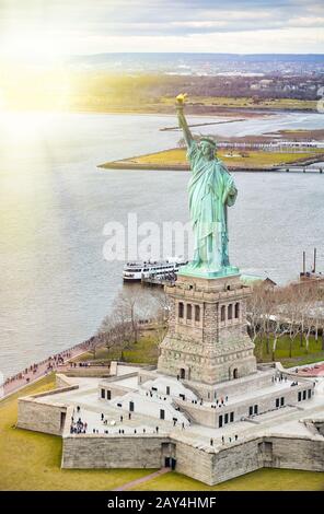 Freiheitsstatue auf Liberty Island und Fähre mit Touristen, New York City. Stockfoto