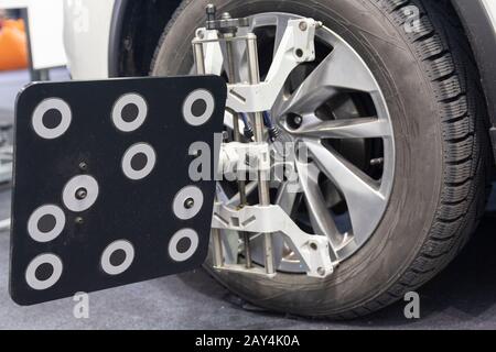 Kfz-Mechaniker montieren Sensor bei der Einstellung der Federung und bei der Ausrichtung der Fahrzeugrader an der Reparaturstation Stockfoto