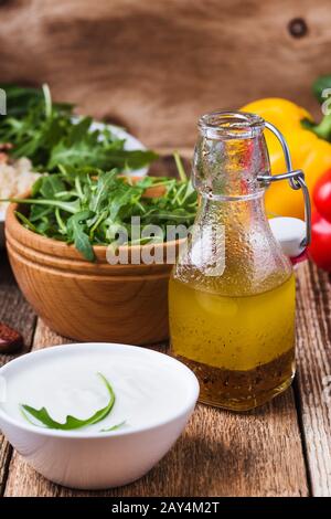 Griechischen Joghurt und hausgemachtes Salatdressing, frisch zubereitenden Salat mit Gemüse, Kräutern und Kichererbsen auf rustikalem Holztisch Stockfoto