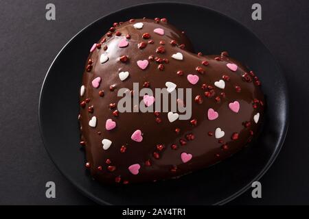 Herzförmige Kuchen und rote Rosen zum Valentinstag oder Muttertag auf schwarzem Hintergrund Stockfoto