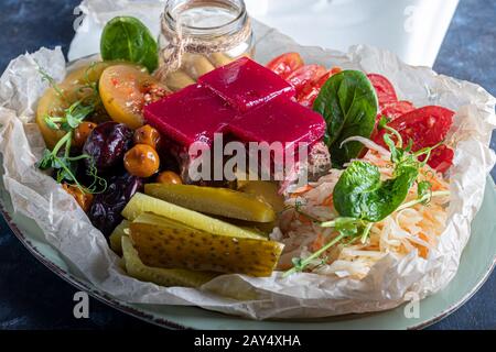 Sellerie und Kartoffelpüree mit roten Fischstücken, garniert mit Kräutern und frischen Gurken. Auf einer weißen Platte mit Zitronenscheiben. Auf einem Holztisch. Kopieren Stockfoto