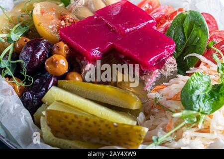 Sellerie und Kartoffelpüree mit roten Fischstücken, garniert mit Kräutern und frischen Gurken. Auf einer weißen Platte mit Zitronenscheiben. Auf einem Holztisch. Kopieren Stockfoto