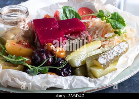 Sellerie und Kartoffelpüree mit roten Fischstücken, garniert mit Kräutern und frischen Gurken. Auf einer weißen Platte mit Zitronenscheiben. Auf einem Holztisch. Kopieren Stockfoto