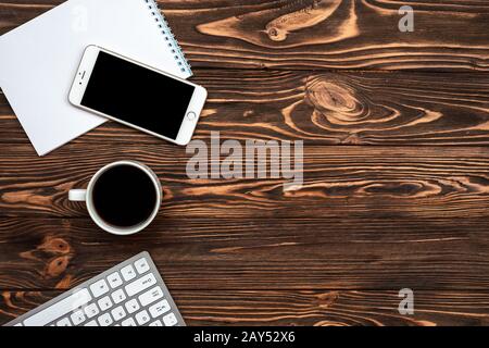 Schreibtisch aus Holz mit Blick auf die Oberseite, Kaffee- und Smartphone-Tasse Stockfoto