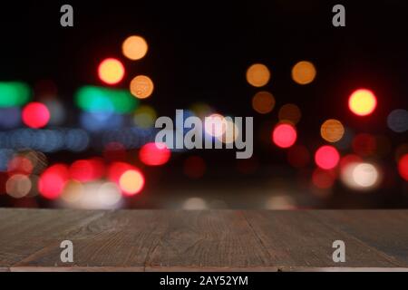 Leerer Holztisch vor abstraktem, verschwommenem Bokeh-Licht des Cafés, Restaurant in der Nacht. Stockfoto