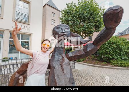 1. August 2019, Luxemburg: Glückliche asien-frau umarmt ihre Zwillingsstatue an der Stadtstraße Stockfoto