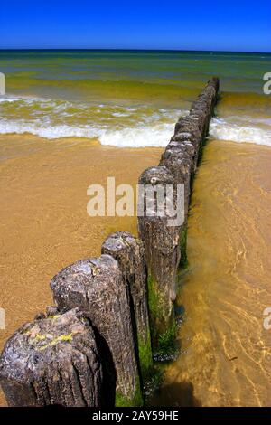 Bunte Meereslandschaft an der Ostseeküste und am sandigen Strand in der Stadt Karwia, Nordpolen, mit noch vorhandenen Holz-Wellenbrecher-Konstruktionen Stockfoto