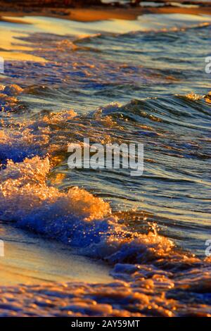 Farbenfrohes Licht bei Sonnenuntergang über den Wellen der Ostsee am Strand und an der Küste des Ferienortes Karwia, Nordpolen, in der Sommersaison Stockfoto