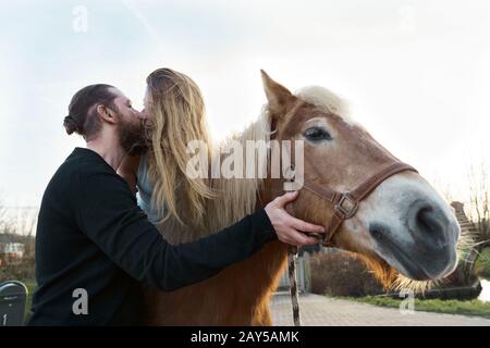 Liebevolles Paar Mann und Frau, Die Ein Pferd Küssen Stockfoto