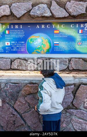 Boy liest die Beschreibungskarte des arktischen Kreises im Weihnachtsmanndorf, Finnland, Lappland, Europa Stockfoto