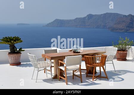 Griechenland: Santorini. Das Dorf Oia und seine Häuser mit weiß getünchten Fassaden. Tisch auf der Terrasse eines Hotels mit Blick auf die Caldera. Stockfoto