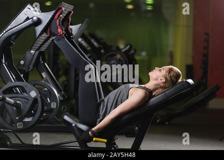 Sportliche Frau mit Gewichten-Presse-Maschine für die Beine. Fitness-Studio. Stockfoto