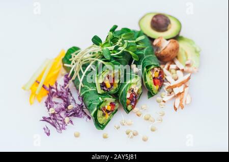 Vegane Frühlings-Grün-Brötchen mit Pfeffer isoliert über weißem Hintergrund mit Avocado, Pilzen, Purpurkohl. Erbsen sprießen auf Rollen. Collard grinst Stockfoto