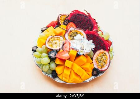 Rote Pitaya-Drachenfrucht, Trauben, Mango und Erdbeere auf Platte vor weißem Hintergrund. Gute Ernährung, vitaminreiche Früchte. Frischer Salat. Tropisch Stockfoto