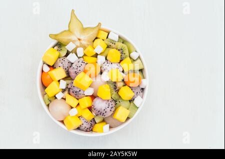 Draufsicht auf frisches exotisches Obst in der Schüssel. Stücke aus weißer Drachenfrucht, Kiwi, Pitaya, Mango und starfruit. Leckeres vegetarisches Dessert zum Essen Stockfoto