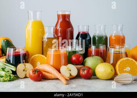 Frischer Saft aus verschiedenen Gemüsen und Obst in Glasgefäßen auf grauem Tisch, isoliert über weißem Hintergrund. Frisch gepresste Produkte. Entgiftungsdiät Stockfoto