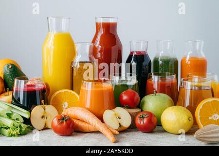 Horizontaler Schuss aus gepresstem Gemüse und Obst in Glasflaschen. Bunte frische Äpfel, Zitrone, Orange, Tomaten und Sellerie gegen weißen Bac Stockfoto