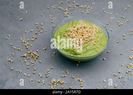 Sauberes Ess- und Entgiftungskonzept. Grüner veganer Smoothie in der Schüssel. Kerne herumsprießen. Gesundes grünes Bio-Rohgericht für Vegeser Stockfoto