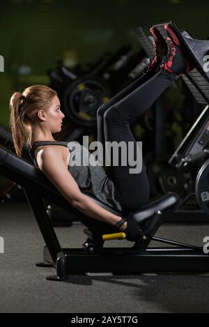 Sportliche Frau mit Gewichten-Presse-Maschine für die Beine. Fitness-Studio. Stockfoto