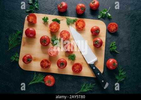 Kirschrottomaten Scheiben mit Messer auf dem Hackbrett zum Herstellen von Ketchup. Organisches Gemüse zum schmecken voller Vitaminsalat. Vegetarische dis Stockfoto