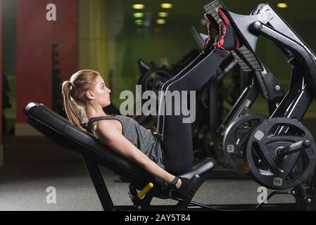 Sportliche Frau mit Gewichten-Presse-Maschine für die Beine. Fitness-Studio. Stockfoto