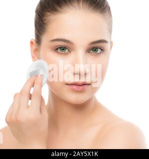 Junge Frau kümmert sich um Gesichtshaut. Perfekte frische Reinigung mit einem Baumwollpolster. Isoliert. Stockfoto