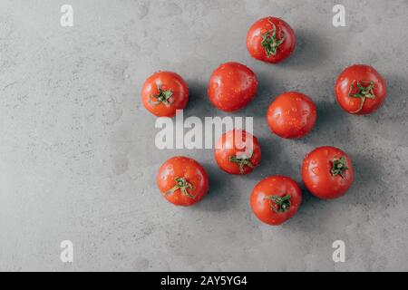 Köstliche rote Tomaten zum Herstellen von Ketchup auf grauem Hintergrund. Gemüse mit Wassertropfen bedeckt. Konzept für Frische und Ernährung. Horizontaler Schuss Stockfoto