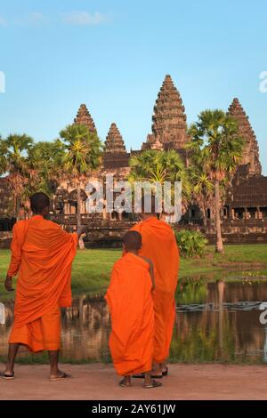 Drei junge Mönch im Angkor Wat, in traditionellen saffronfarbenen Gewändern, bewundern den majestätischen Tempel. Stockfoto