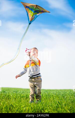 Kleiner Junge spielt mit seinem Kite in einem grünen Feld. Stockfoto