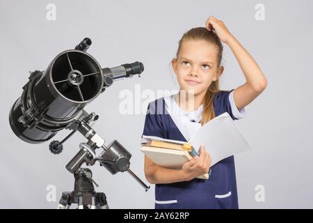 Schulmädchen gefragt und gesucht bis zu lesen ein Lehrbuch stehen am Teleskop Stockfoto