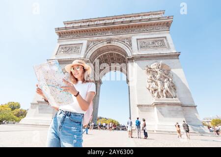 Die fröhliche asiatische Touristin genießt den Blick auf den majestätischen und berühmten Triumphbogen oder Triumphbogen. Alleinreisen und Reisen nach Paris und Frankreich Stockfoto