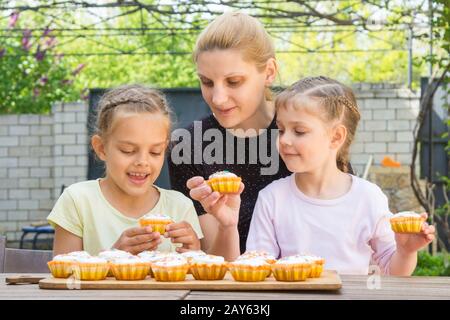 Mutter und zwei Töchter sitzen am Tisch mit Ostern Cupcakes und sie gestiegen Stockfoto