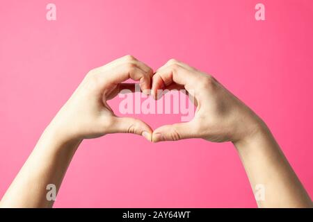 Frau hält die Hände in Form eines Herzens auf pinkfarbenem Hintergrund Stockfoto
