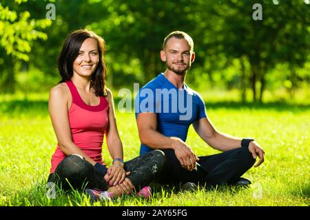 Junger Mann und Frau beim Yoga im sonnigen Sommerpark Stockfoto