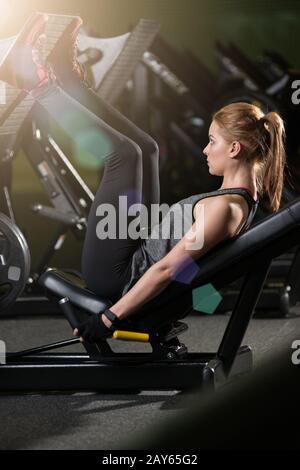 Sportliche Frau mit Gewichten-Presse-Maschine für die Beine. Fitness-Studio. Stockfoto