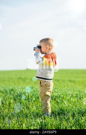 Kleiner Junge mit einer alten Kamera schießen im Freien. Stockfoto