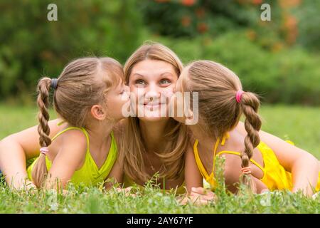 Zwei Töchter küssen Mutter liegen auf der Wiese ein Picknick, Mutter blickte Spaß Stockfoto