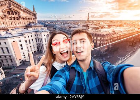 Liebevolles Paar Asiatisches Mädchen und europäischer Kerl umarmen sich und nehmen ein selfie auf der Aussichtsplattform mit Blick auf die Pariser Landschaft. Flitterwochen in Frankreich Stockfoto