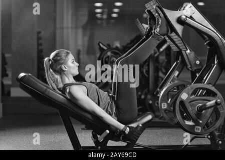 Sportliche Frau mit Gewichten-Presse-Maschine für die Beine. Fitness-Studio. Stockfoto