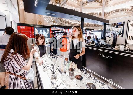 27. Juli 2019, Paris, Frankreich: Asiatische Mädchen riechen einen Tester des neuen Dufts des beliebten Parfüms in den Galeries Lafayette Stockfoto