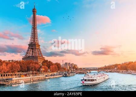 Die Hauptattraktion von Paris und ganz Europa ist der Eiffelturm in den Strahlen der untergehenden Sonne am Ufer der seine mit Kreuzfahrtschiffen Stockfoto