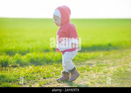 Glückliche kleine Mädchen zu Fuß auf der Wiese und Blick auf Sonne Stockfoto