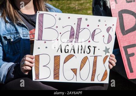 Mädchen in Jeansjacke mit hausgemachtem Schild - Babes Against Bigots - mit Sternen und Schmucksteinen darauf Stockfoto